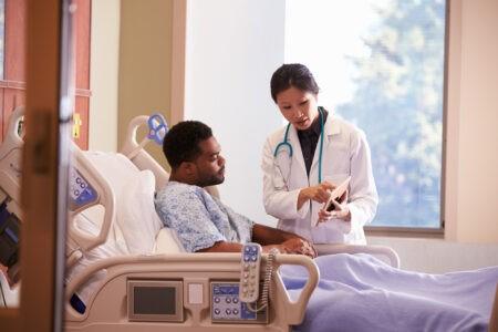 Patient In Hospital Bed Talking with Doctor